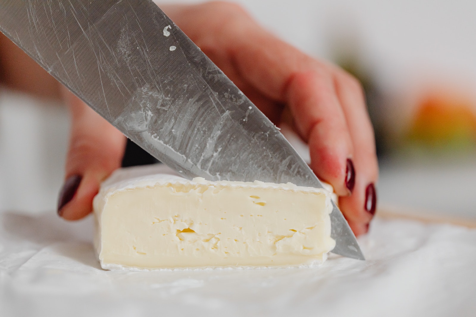Hands of a Woman Slicing White Cheese