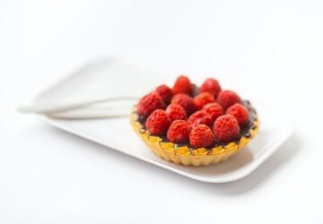 photo of chocolate cupcake with berry toppings on white ceramic plate