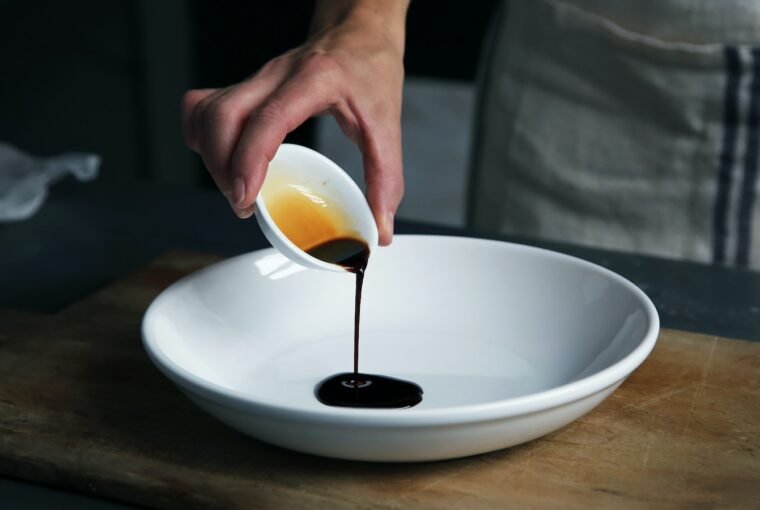 person dripping black liquid from small white ceramic bowl to big white ceramic bowl