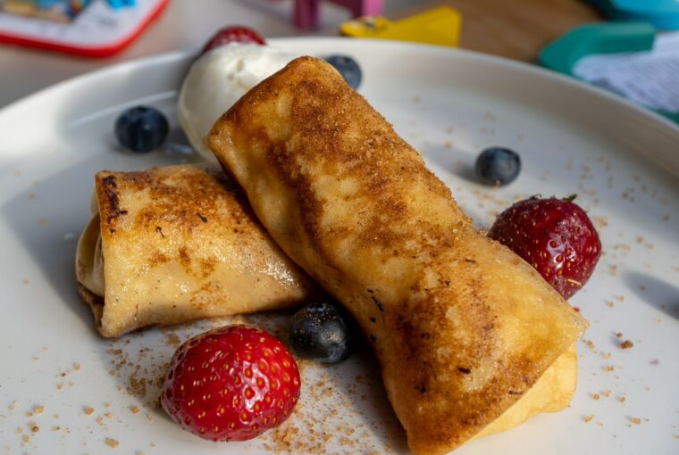 Closeup shot of cheese blintz with strawberries and blueberries on a white plate