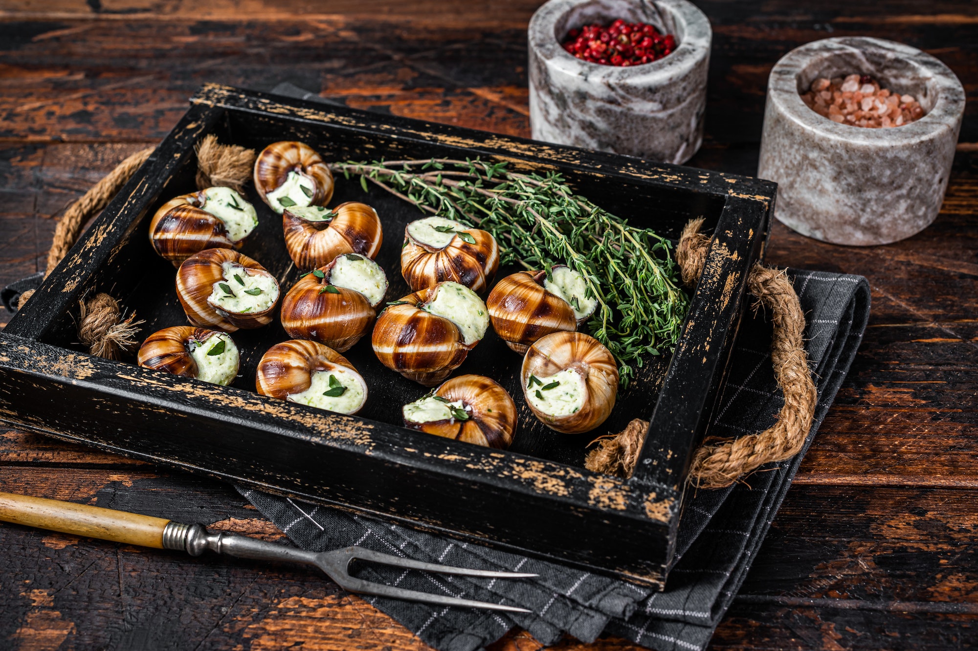 French gourmet - Escargot Snails with garlic butter in a wooden tray. Wooden background. Top view