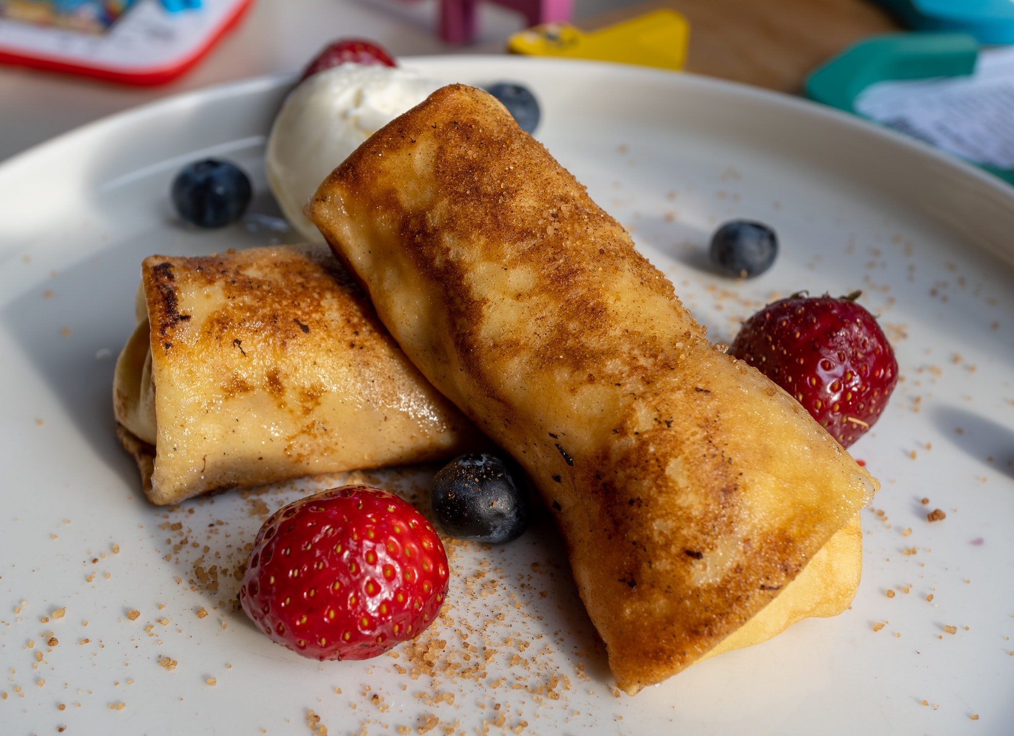 Closeup shot of cheese blintz with strawberries and blueberries on a white plate