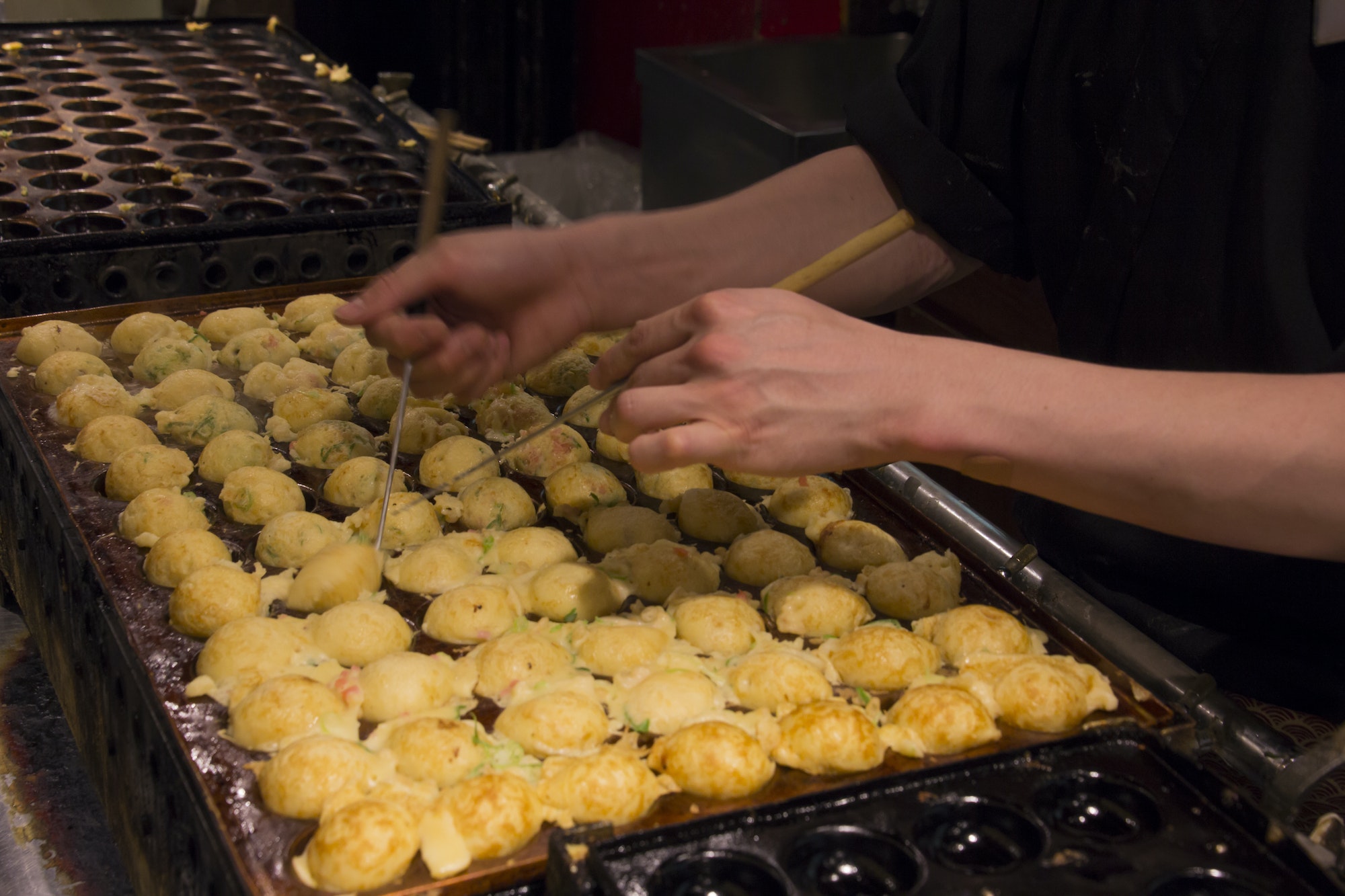 Cook rolling takoyaki in a traditional Japanese restaurant in Osaka (Japan)